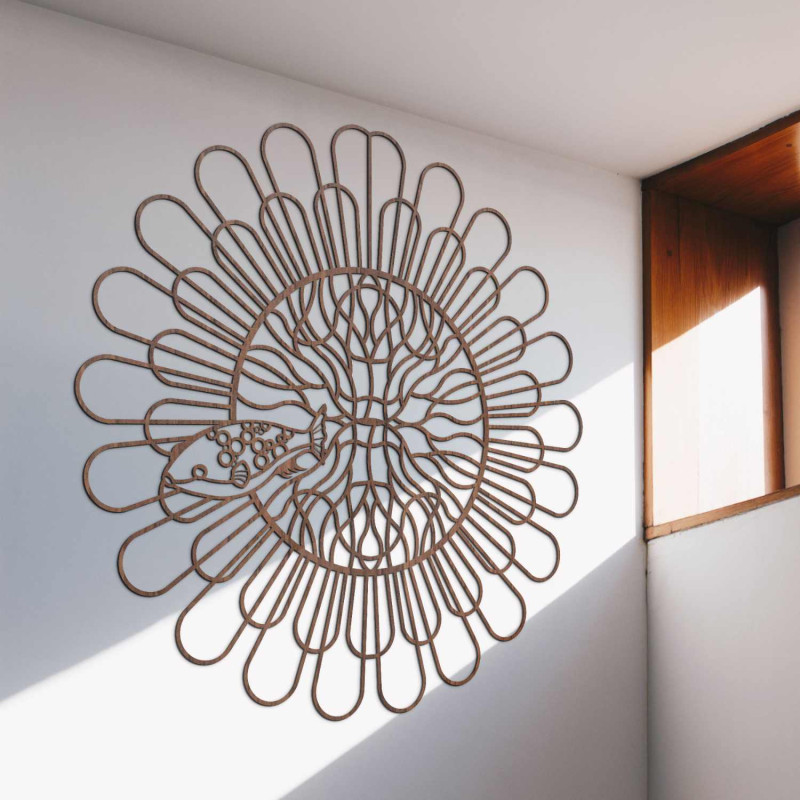 Čierna drevená mandala s rybou na bielej stene v modernom byte