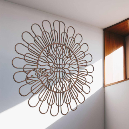 Čierna drevená mandala s rybou na bielej stene v modernom byte